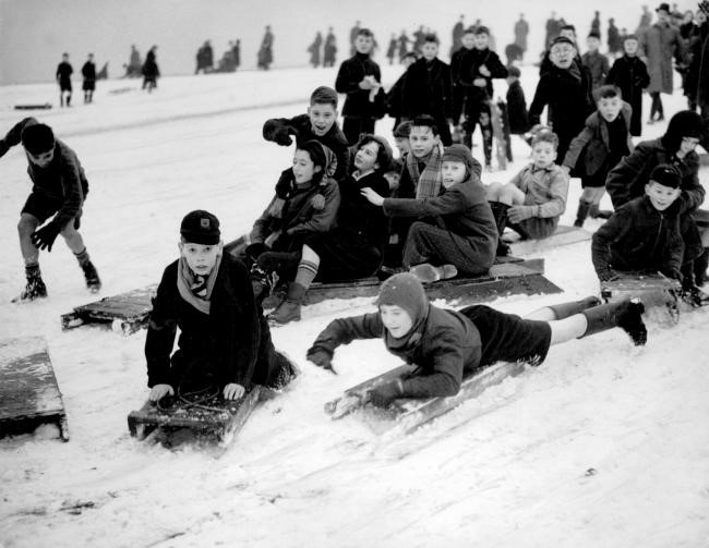 Note the balaclavas, short trousers, wellies and homemade sledges – children were fearless then!